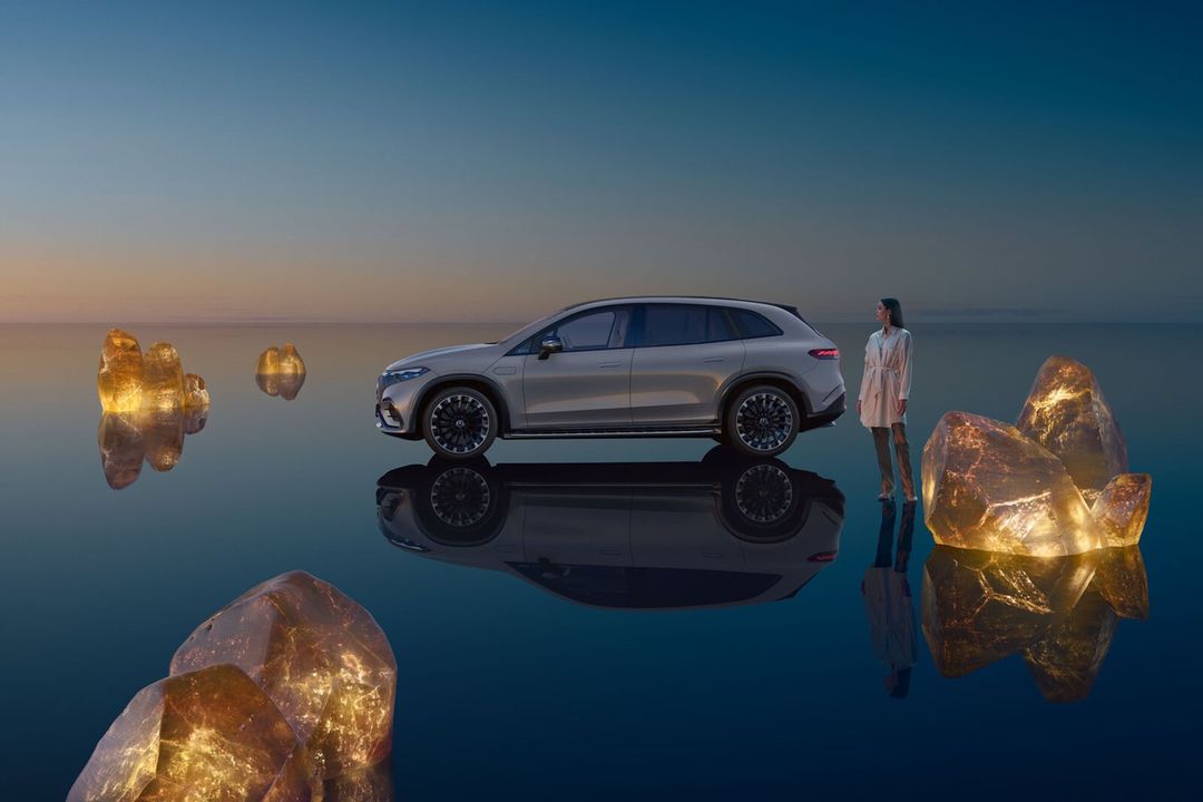 Luxury SUV showcased next to a woman and golden crystal formations on a reflective surface under a gradient sky at dusk.