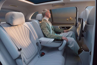 Man seated in the luxury white leather interior of a car looking out the window