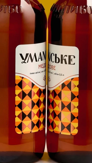 Close-up of two brown glass bottles with labels featuring a geometric pattern and Cyrillic text, set against a yellow background.