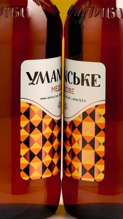Close-up of two brown glass bottles with labels featuring a geometric pattern and Cyrillic text, set against a yellow background.