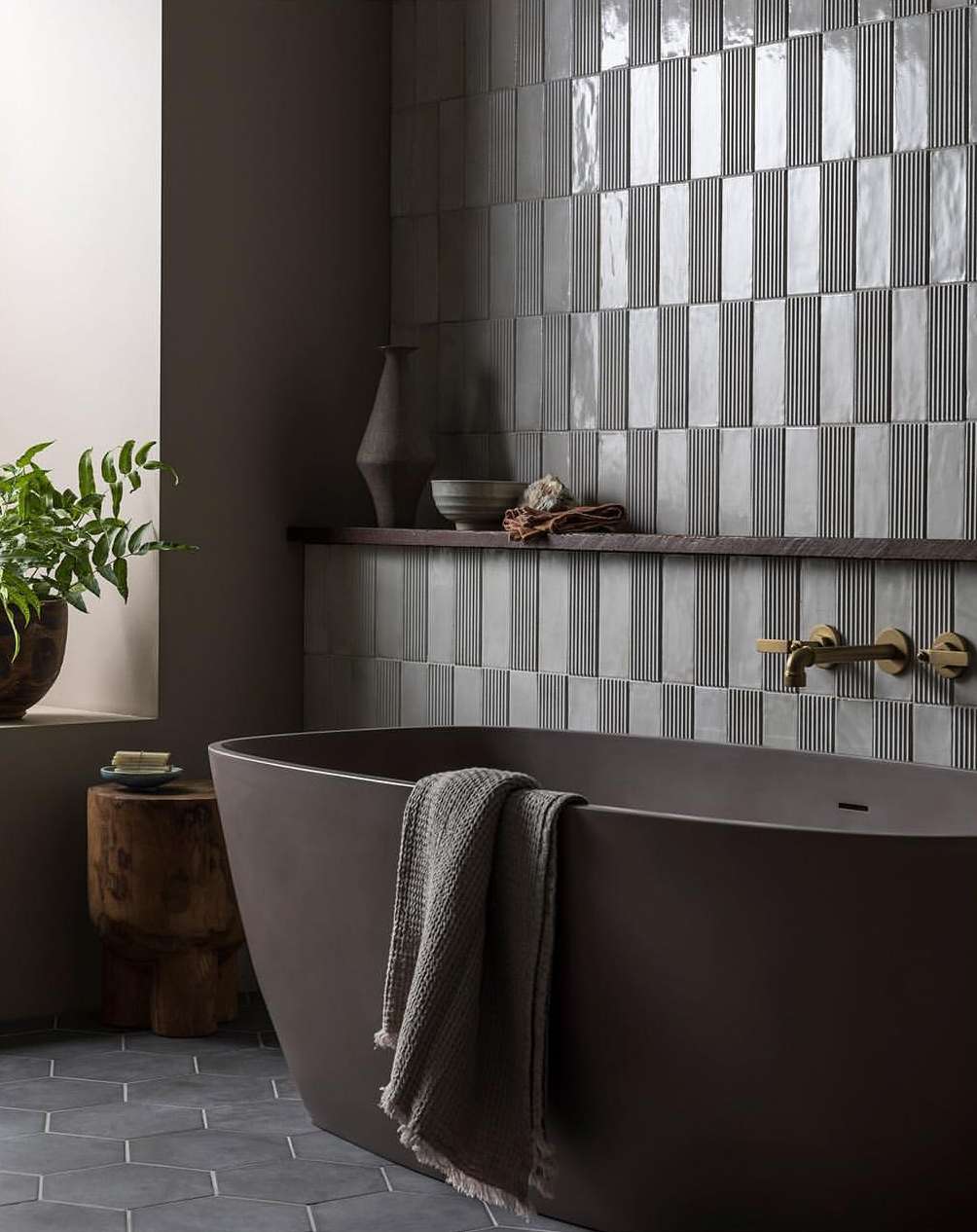 Modern bathroom design featuring a brown bathtub, geometric tile wall, and wooden accents creates a warm, inviting spa atmosphere.