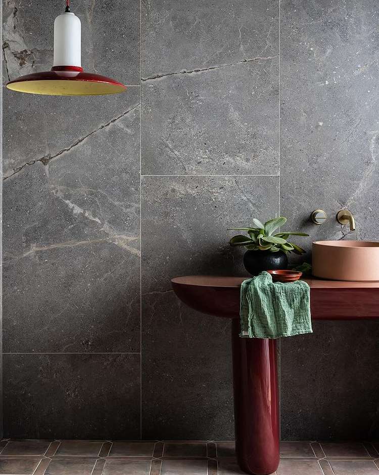 Interior design with gray stone tile wall, terracotta sink on a matching stand, potted succulent, and a pendant light fixture.