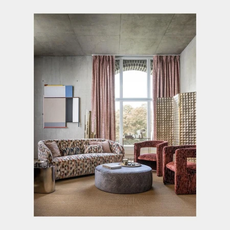 Modern interior living room with patterned sofa, round ottoman, and large arched window with patterned curtains.