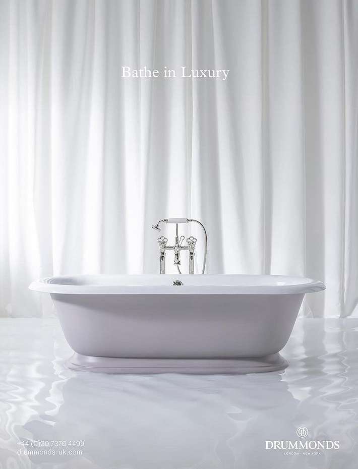 Elegant bathroom interior featuring a freestanding bathtub with chrome fixtures against a backdrop of white drapery, bathed in soft light.
