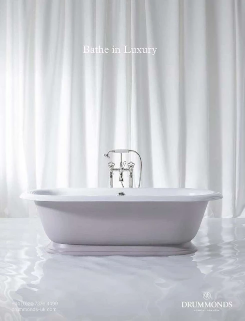 Elegant bathroom interior featuring a freestanding bathtub with chrome fixtures against a backdrop of white drapery, bathed in soft light.