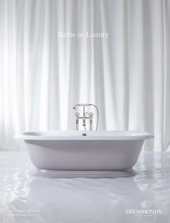 Elegant bathroom interior featuring a freestanding bathtub with chrome fixtures against a backdrop of white drapery, bathed in soft light.