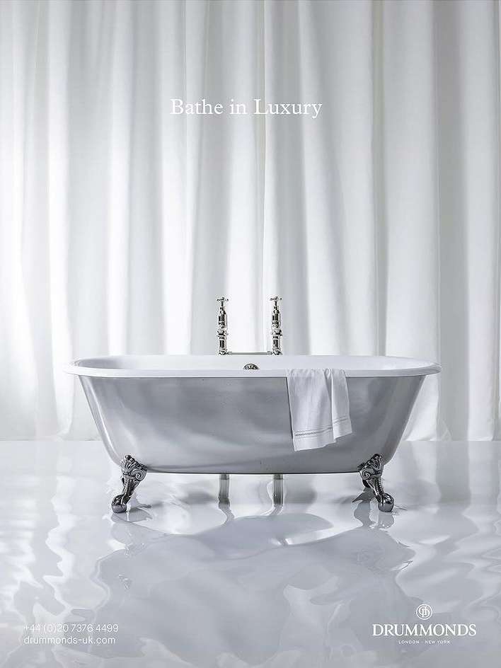 Elegant clawfoot bathtub with silver finish and chrome fixtures, complemented by a white towel and sheer white curtains.