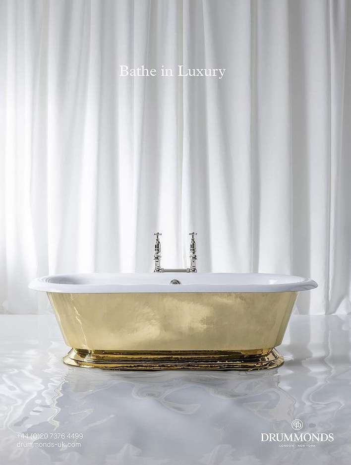 Elegant gold and white bathtub with silver fixtures is showcased in a bright bathroom setting with light-colored water effects.
