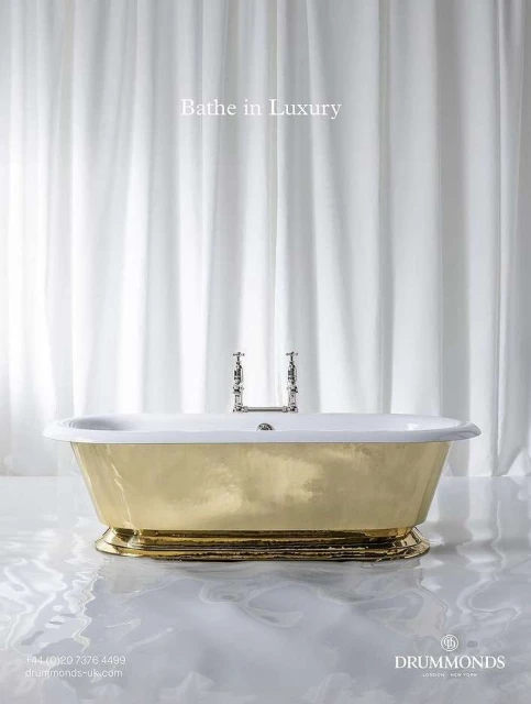Elegant gold and white bathtub with silver fixtures is showcased in a bright bathroom setting with light-colored water effects.