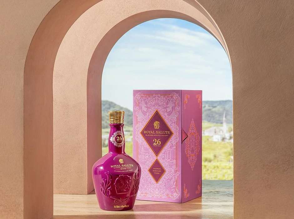 Royal Salute 26-year-old blended Scotch whisky bottle and decorative box set against an outdoor scene through an architectural archway.