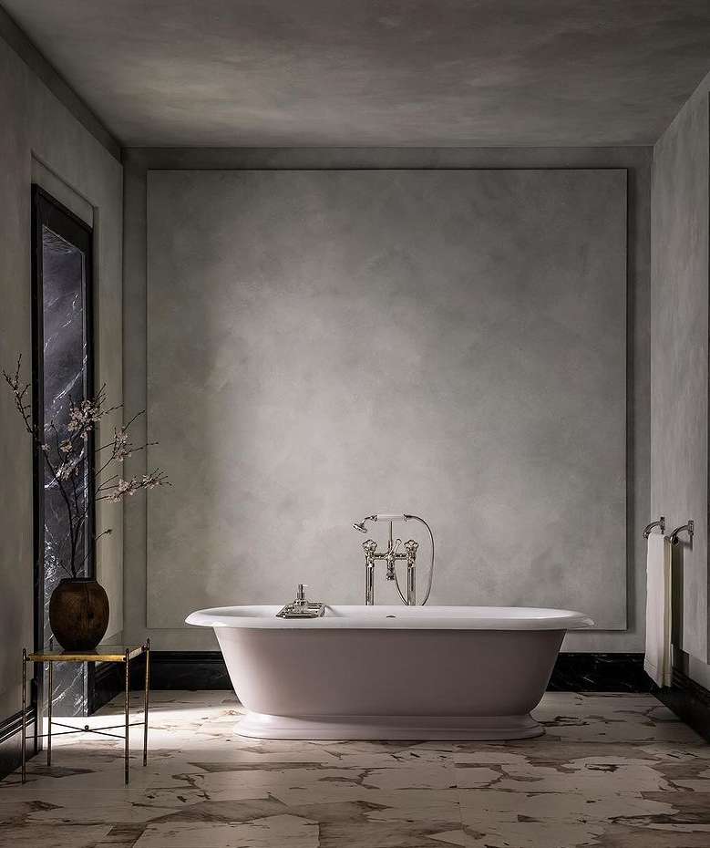 Indoor bathroom scene showcases a freestanding bathtub, marble floors, textured walls, and metal fixtures, evoking a modern aesthetic.