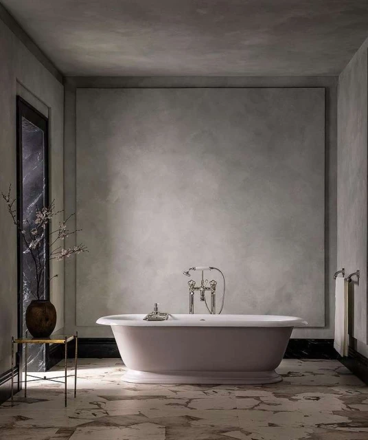 Indoor bathroom scene showcases a freestanding bathtub, marble floors, textured walls, and metal fixtures, evoking a modern aesthetic.