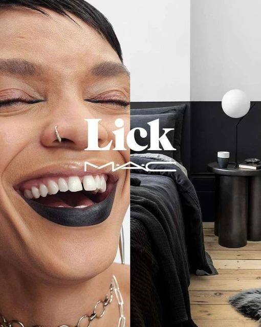 Close-up of a smiling woman with dark lipstick and a modern bedroom with black bedding and a table lamp; makeup advertisement.