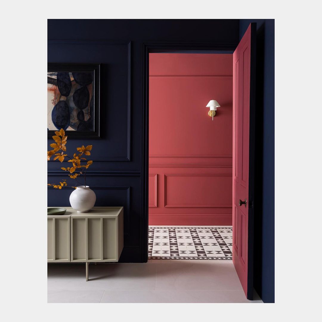 Interior with navy and red walls, cream-colored sideboard, and patterned tile floor creates a stylish and inviting living space.