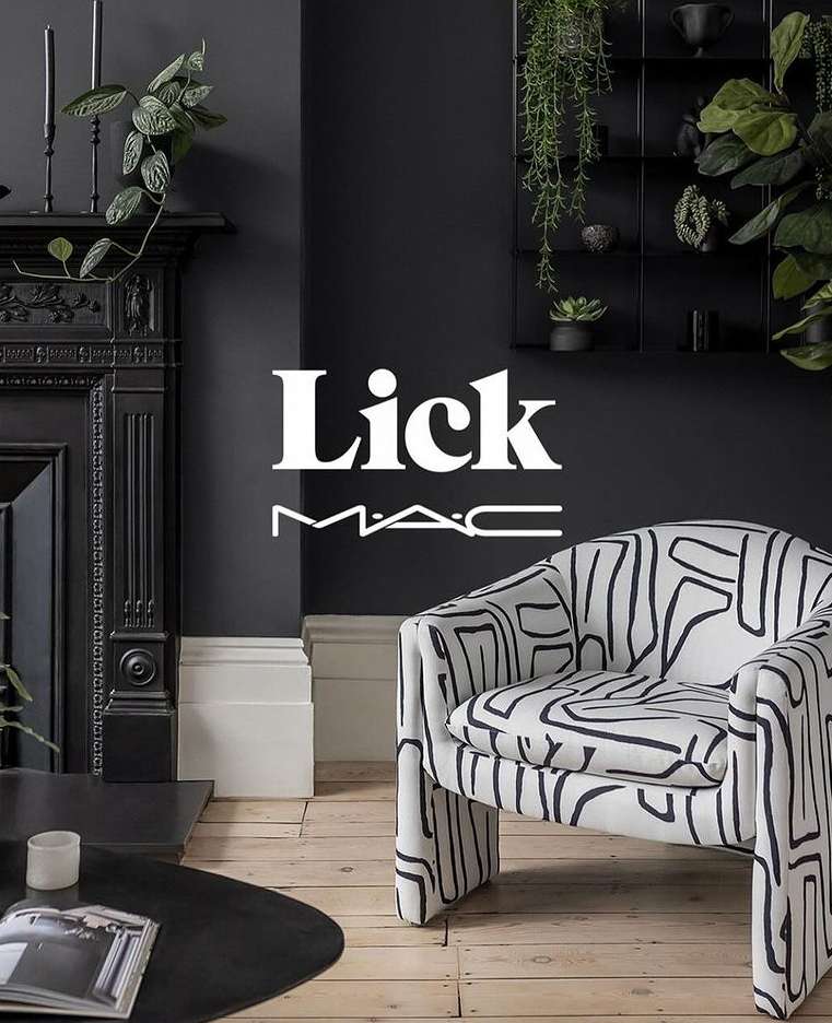 Interior of a living room with a patterned armchair, dark gray walls, a fireplace, and plant decorations creating a cozy ambiance.