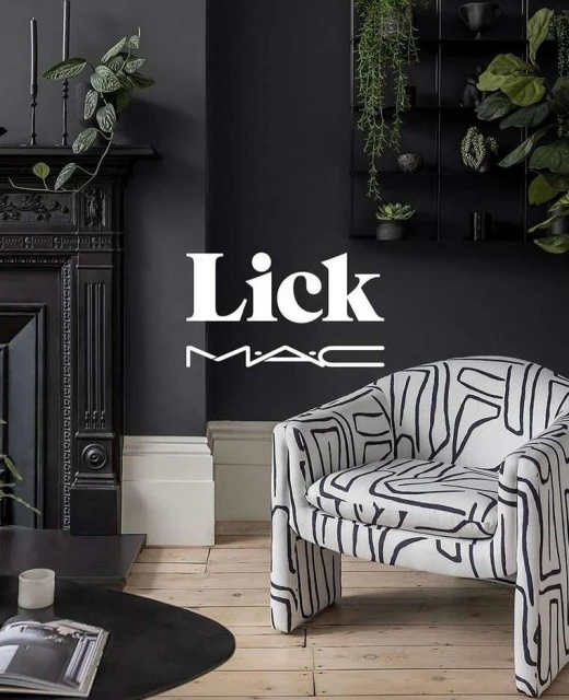 Interior of a living room with a patterned armchair, dark gray walls, a fireplace, and plant decorations creating a cozy ambiance.