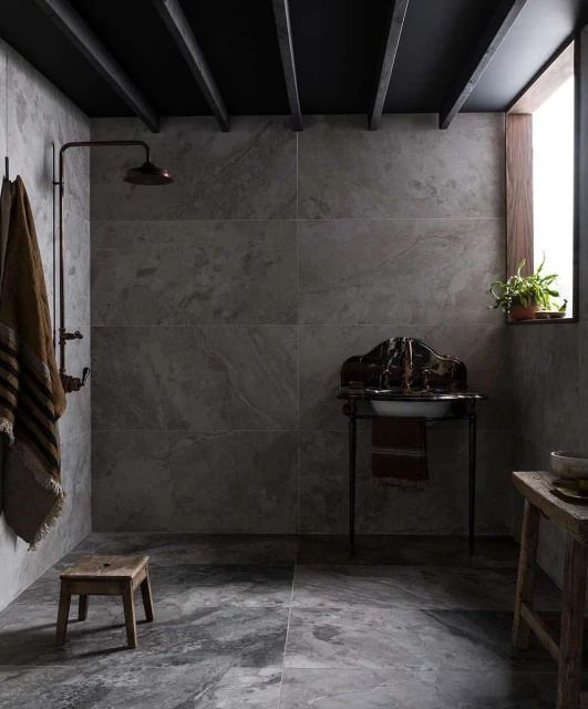 Rustic bathroom interior with stone walls, open shower, stool, antique sink, and wooden ceiling beams creates a minimalist aesthetic.