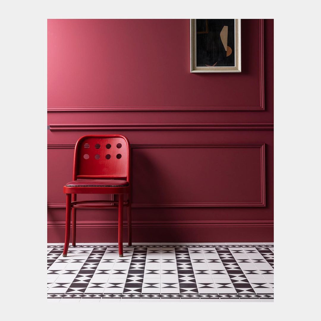 Interior design featuring a red chair against a deep red wall with patterned floor, creating a bold, monochromatic look.