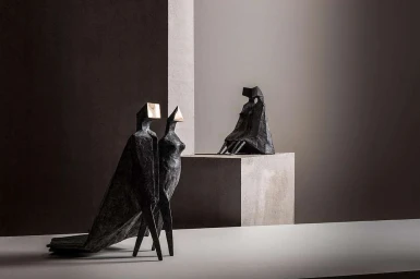 Abstract dark textured metallic sculptures displayed on minimalist platforms against a neutral gradient background