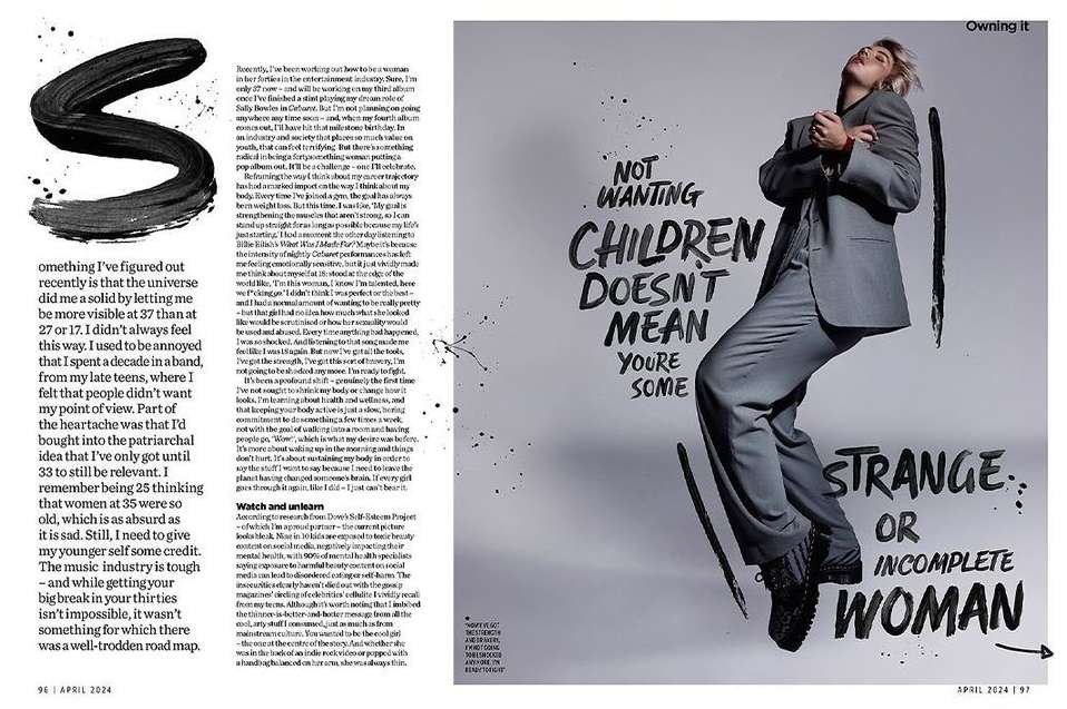 Editorial magazine spread features a woman in an oversized suit next to bold typography against a light grey background.