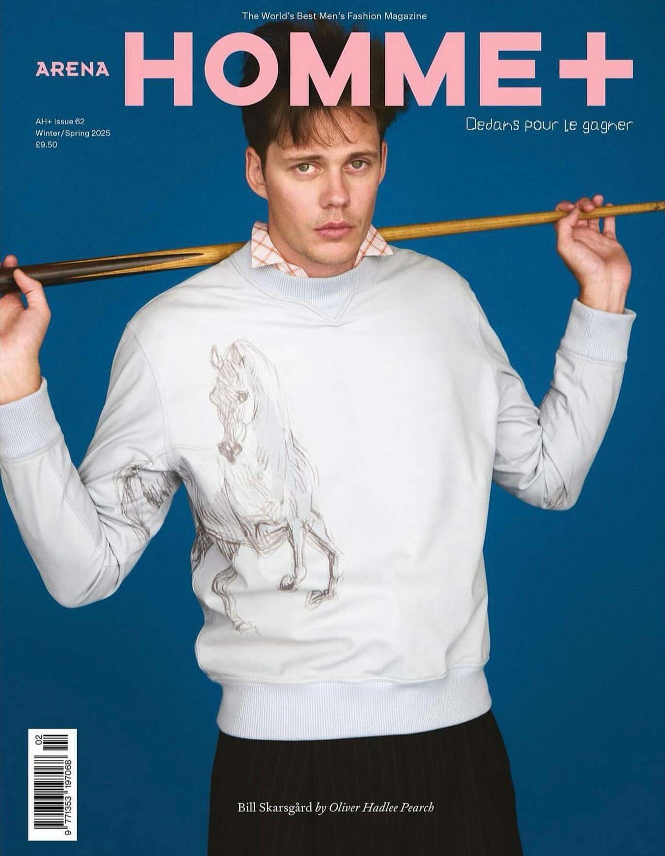 Magazine cover featuring a man in a sweatshirt with a horse graphic, holding a pool cue against a blue background. Fashion editorial.