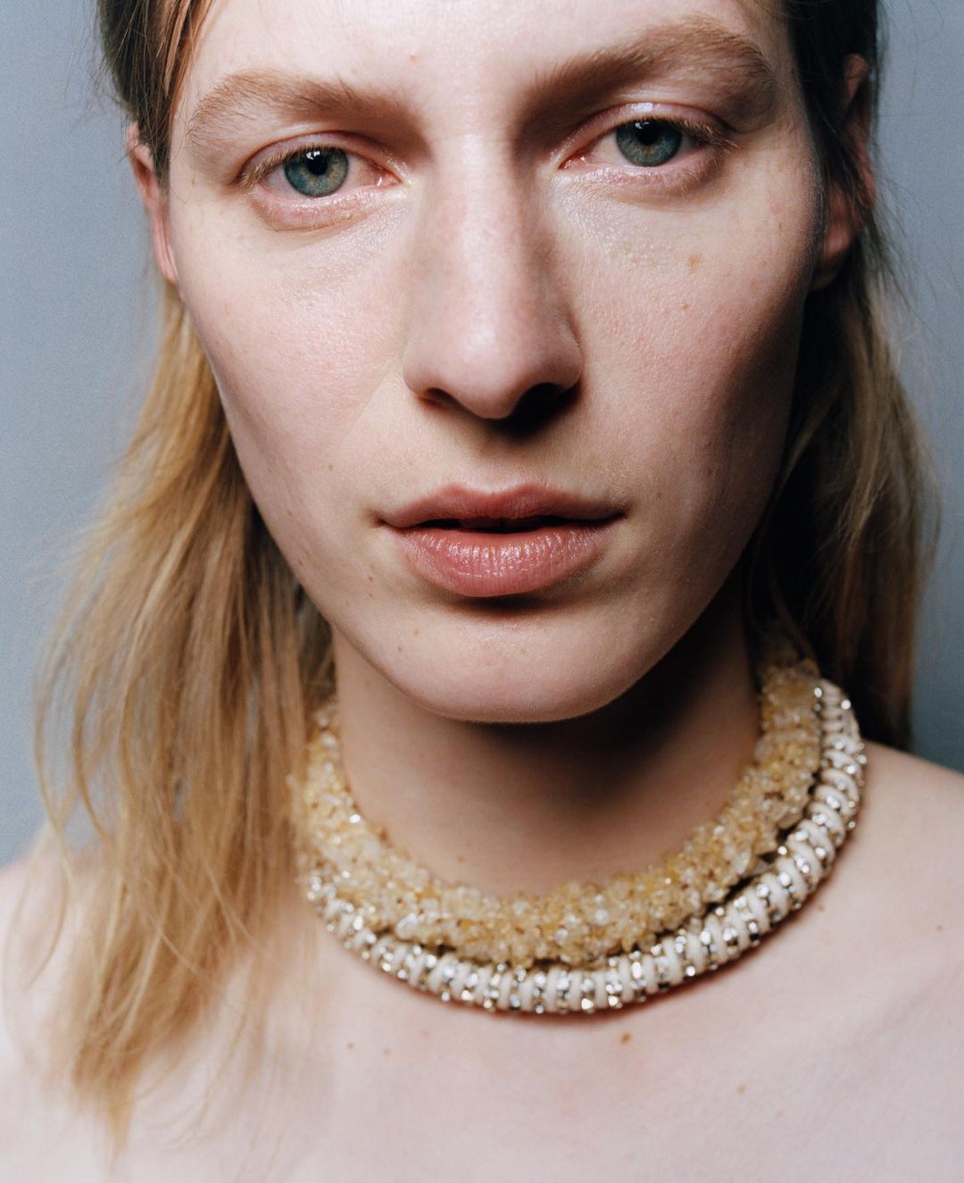 Close-up portrait of a woman wearing layered beaded necklaces by Oliver Hadlee Pearch in New York