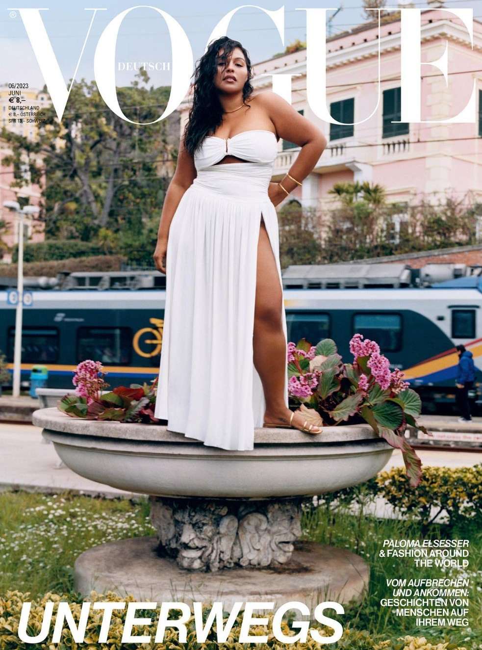 Vogue Deutsch cover featuring a plus-size woman in white dress posing on a stone planter with a train and buildings in the background.