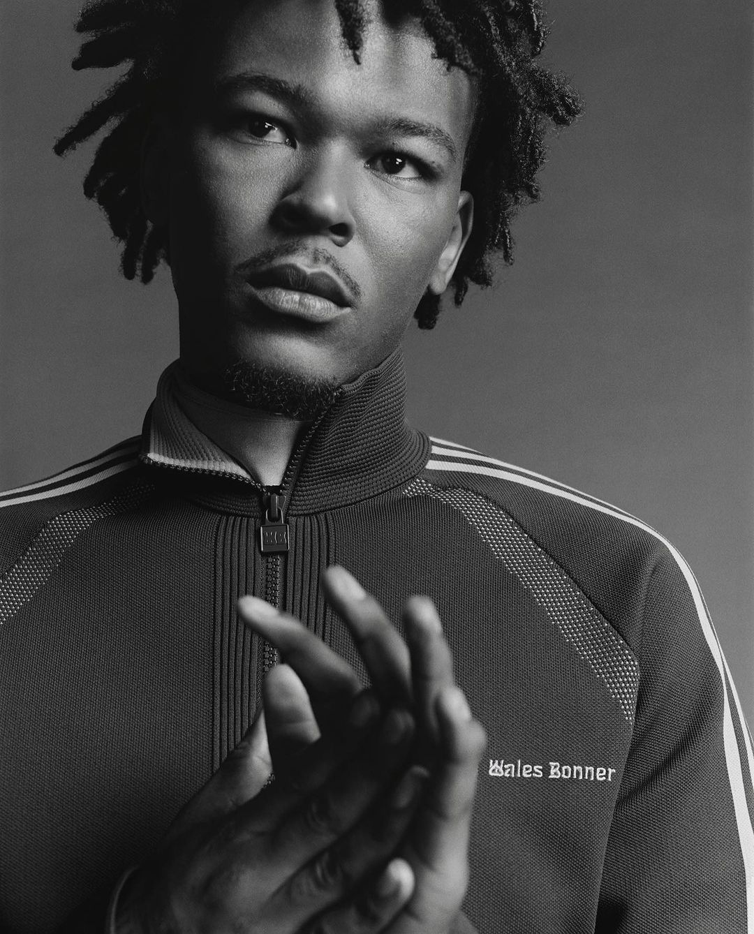 Portrait of a Black man with dreadlocks wearing a zipped track jacket by Oliver Hadlee Pearch in New York.