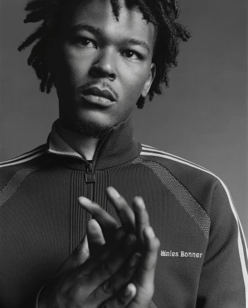 Portrait of a Black man with dreadlocks wearing a zipped track jacket by Oliver Hadlee Pearch in New York.
