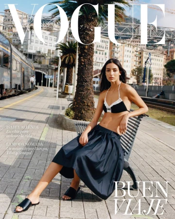 Vogue Espana cover featuring a woman in a black and white bikini top and navy skirt sitting on a bench at a train station.