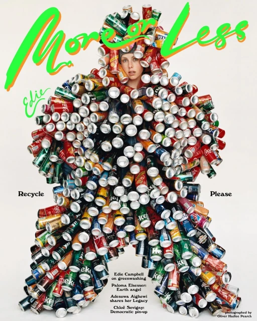 Adult female poses in a tan studio wearing a full body suit entirely made from crushed soda cans and with the text 'More or Less'.