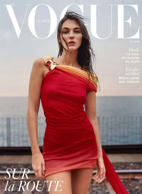 Vogue France magazine cover featuring a woman in a red dress with a gradient hemline, standing on train tracks, against a sky backdrop.