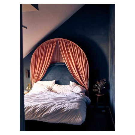 Canopy bed with white bedding in a dark blue room with bedside table and wall lighting provides a cozy, intimate interior design.
