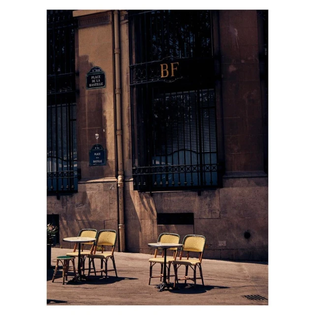 Outdoor cafe setting in Paris, featuring empty tables and chairs outside a building with classic French architectural details.