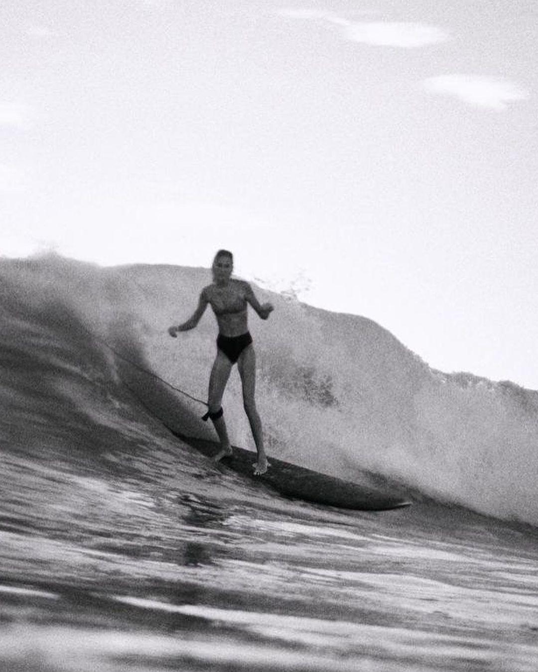 A surfer rides a large wave in a black and white image, showcasing the sport of surfing and the power of the ocean.