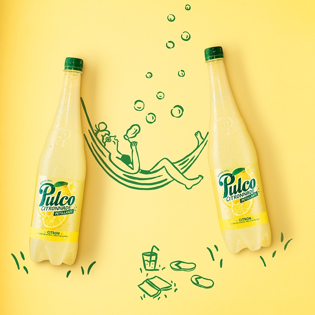 Two bottles of Pulco Citronnade flank a drawing of a woman on a hammock with beverages, creating a summery, refreshing scene.