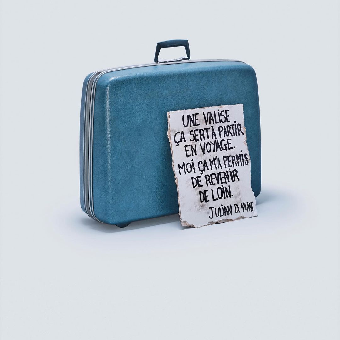 Turquoise vintage suitcase with a handwritten note in French that says: "A suitcase, that is certainly to leave on a trip."