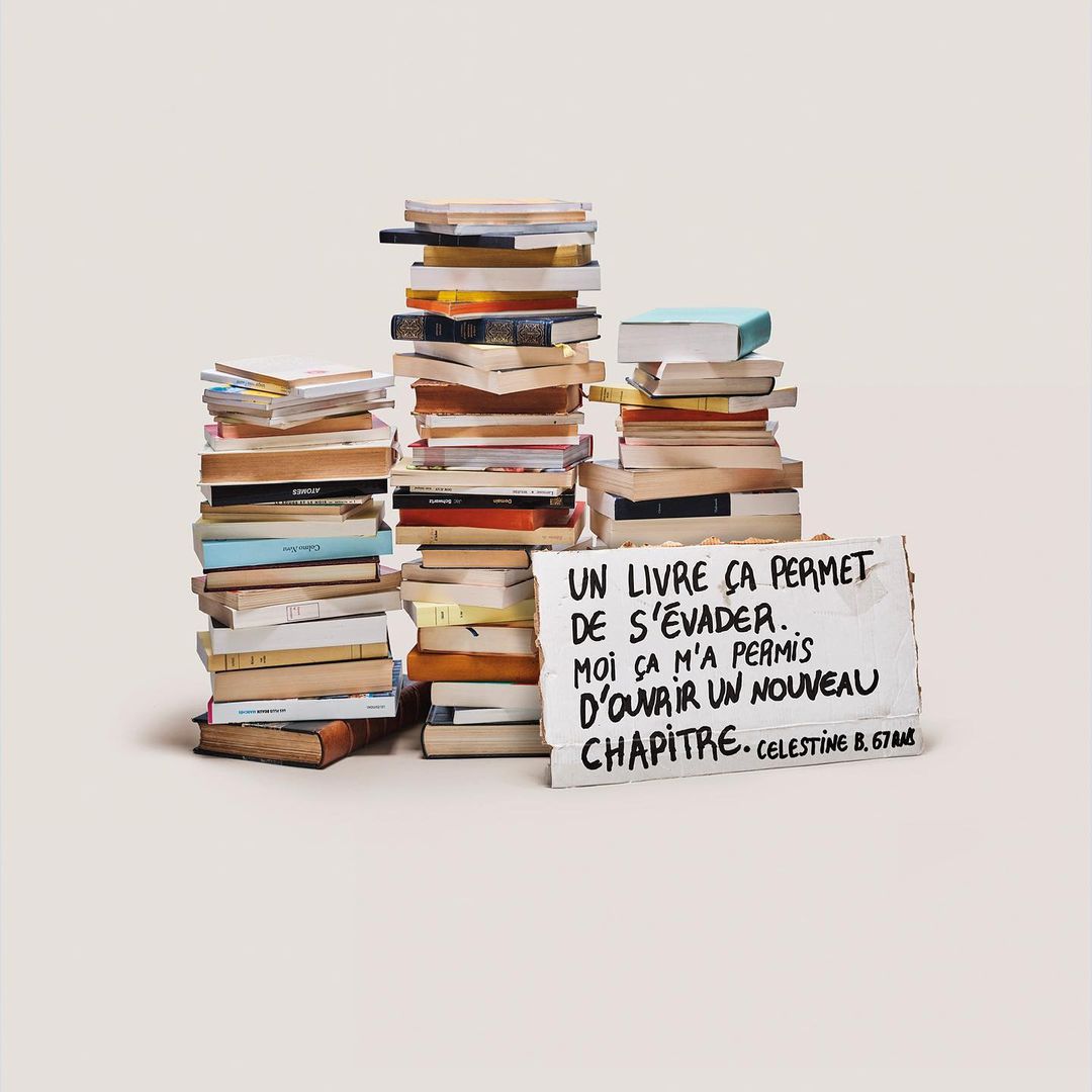 Three stacks of books with a handwritten sign in front, stacked on a white surface in a well-lit indoor setting. Reading concept.