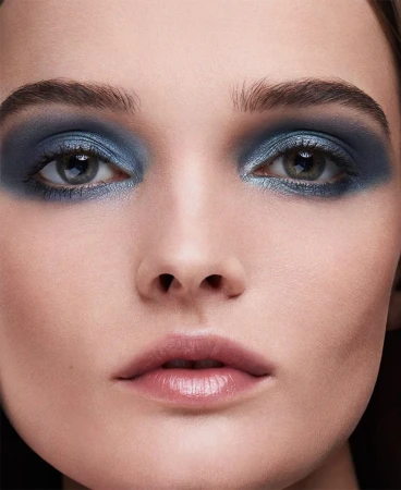 Close-up beauty portrait of a woman with dramatic blue eyeshadow and glossy nude lips photographed by Olivier Rose.