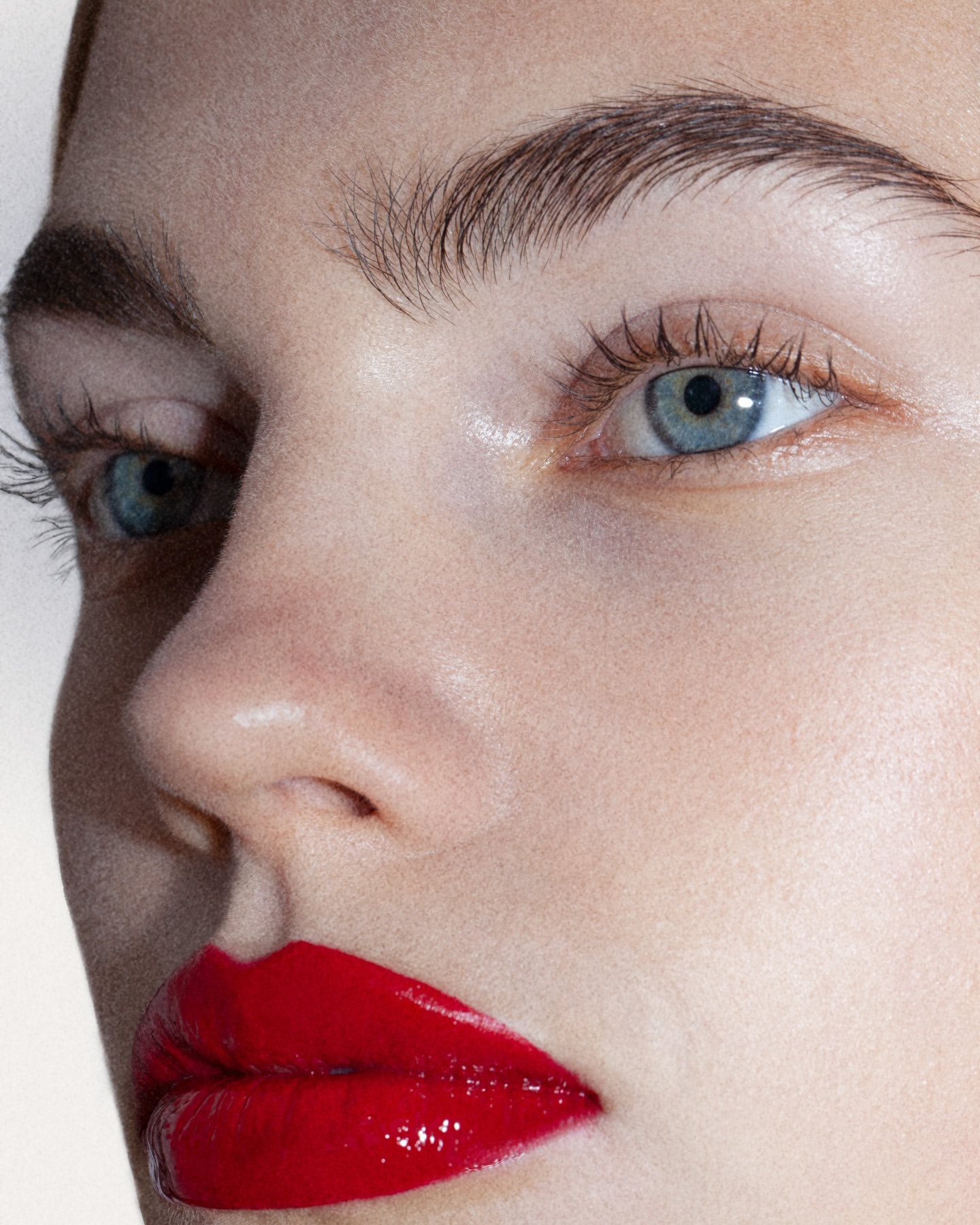 Extreme close up beauty portrait of a woman with bright red glossy lipstick and blue eyes captured by Olivier Rose