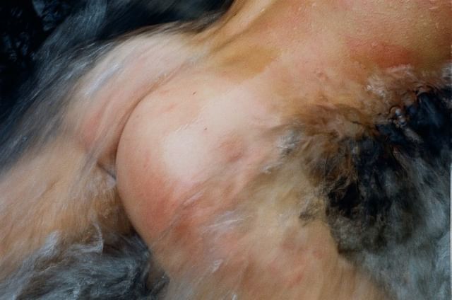 Abstract image of flowing water over bare human skin, creating a textured and dynamic composition in light brown and white tones.
