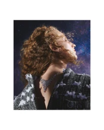 Model with curly red hair wearing a tweed jacket and diamond necklace against a starry cosmic background