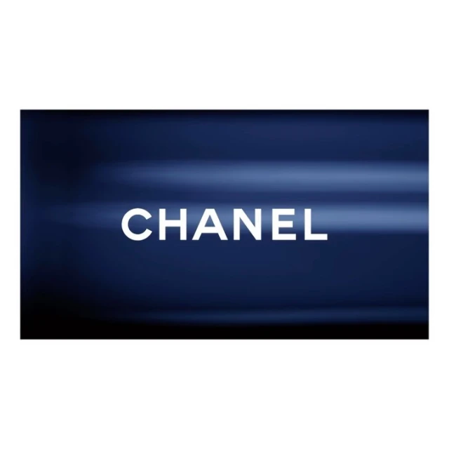 Bright white "CHANEL" text against a dark blue, softly blurred background in a horizontal product shot, ideal for beauty advertising.