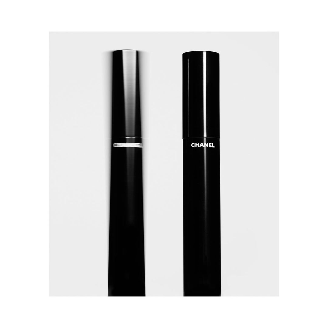 Two black Chanel cosmetic containers stand on a bright white surface in a studio product shot emphasizing minimalist design and luxury beauty.