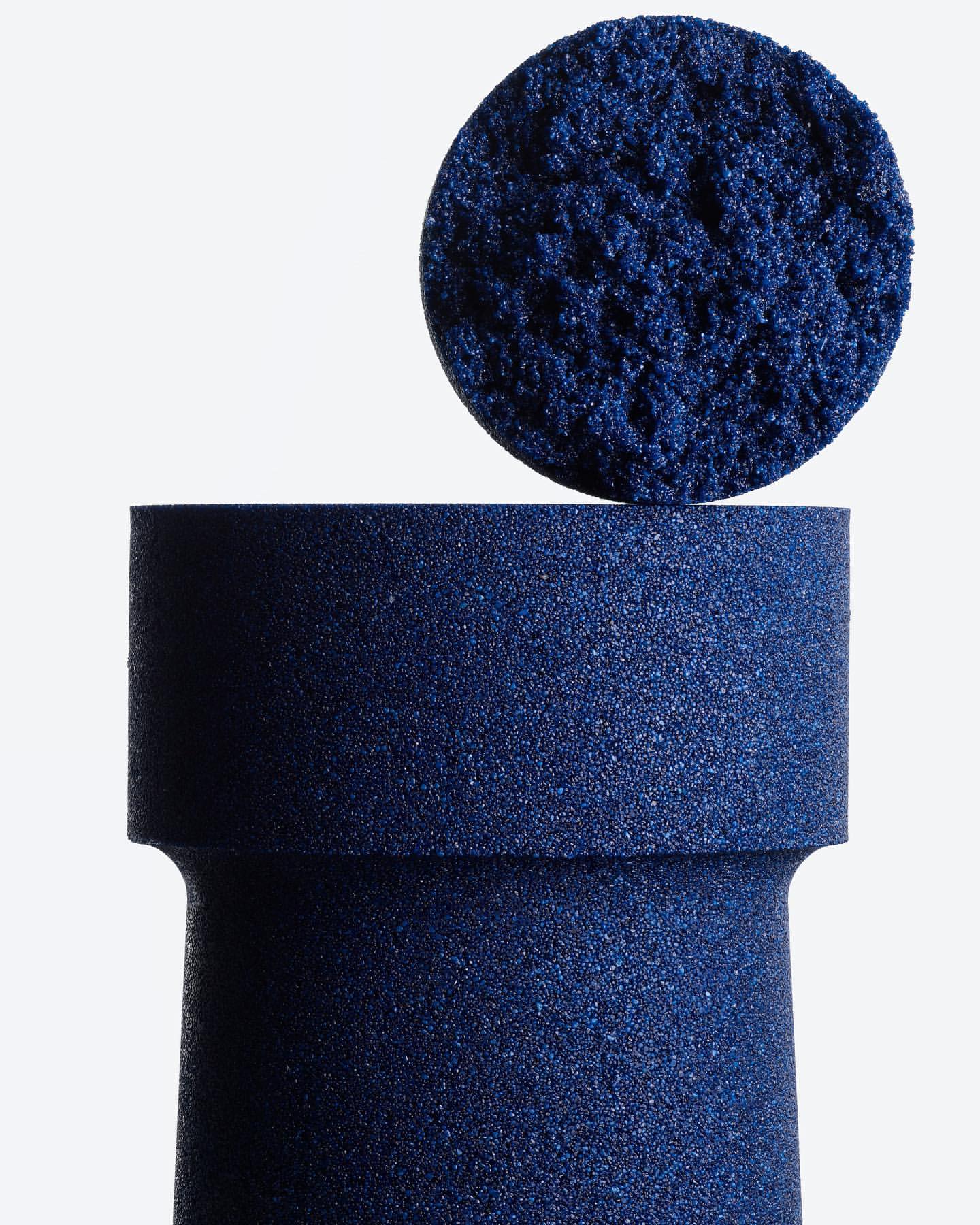 Navy blue textured foam column with round top piece, isolated on white. Abstract design, clean background, and cylinder shape.