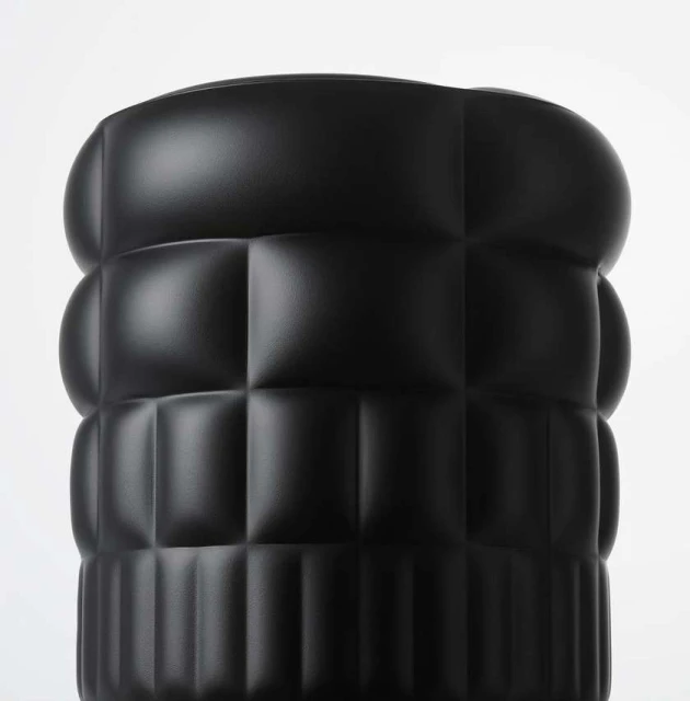 Close-up of a black textured cylinder with rounded edges and a grid pattern against a plain white background, showcasing modern design.