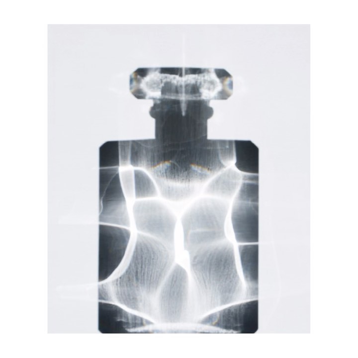 Abstract view of transparent perfume bottle with visible refraction patterns on a white background in a studio lighting environment.