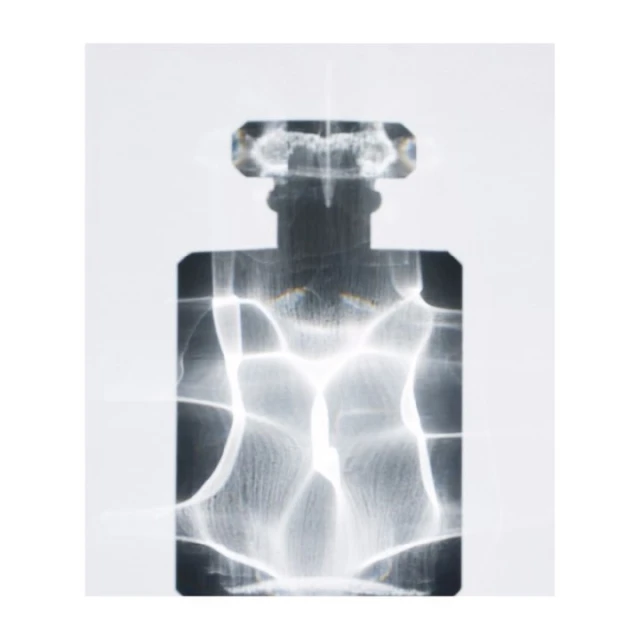 Abstract view of transparent perfume bottle with visible refraction patterns on a white background in a studio lighting environment.