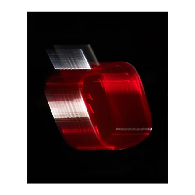 Abstract motion blur photograph of a red object against a black background, creating a sense of speed and movement.