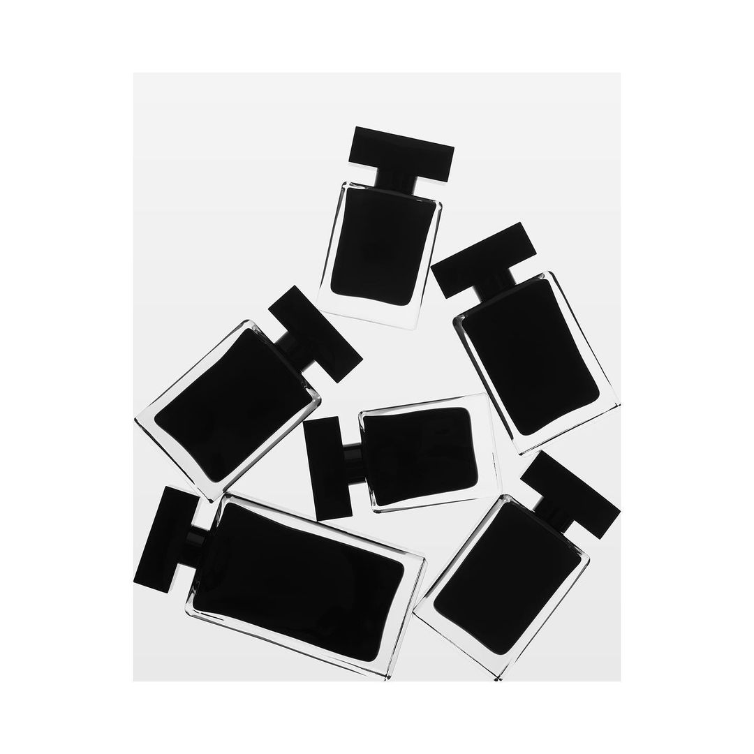 Arrangement of rectangular black perfume bottles with a clear border on a light background, showcasing minimalist and beauty product.